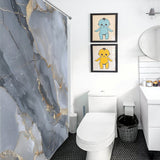 A bathroom with a toilet, vanity, and a luxurious Gray Gold Stripe Abstract Marble Texture Art Shower Curtain-Cottoncat. Two framed artworks of cartoon characters hang on the wall above the toilet.