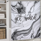 Bathroom with a black and white marble-themed shower curtain bearing the Funny Letters Black and White Marble Get Naked Shower Curtain-Cottoncat in cursive script. A shelving unit on the left holds white towels and woven baskets.