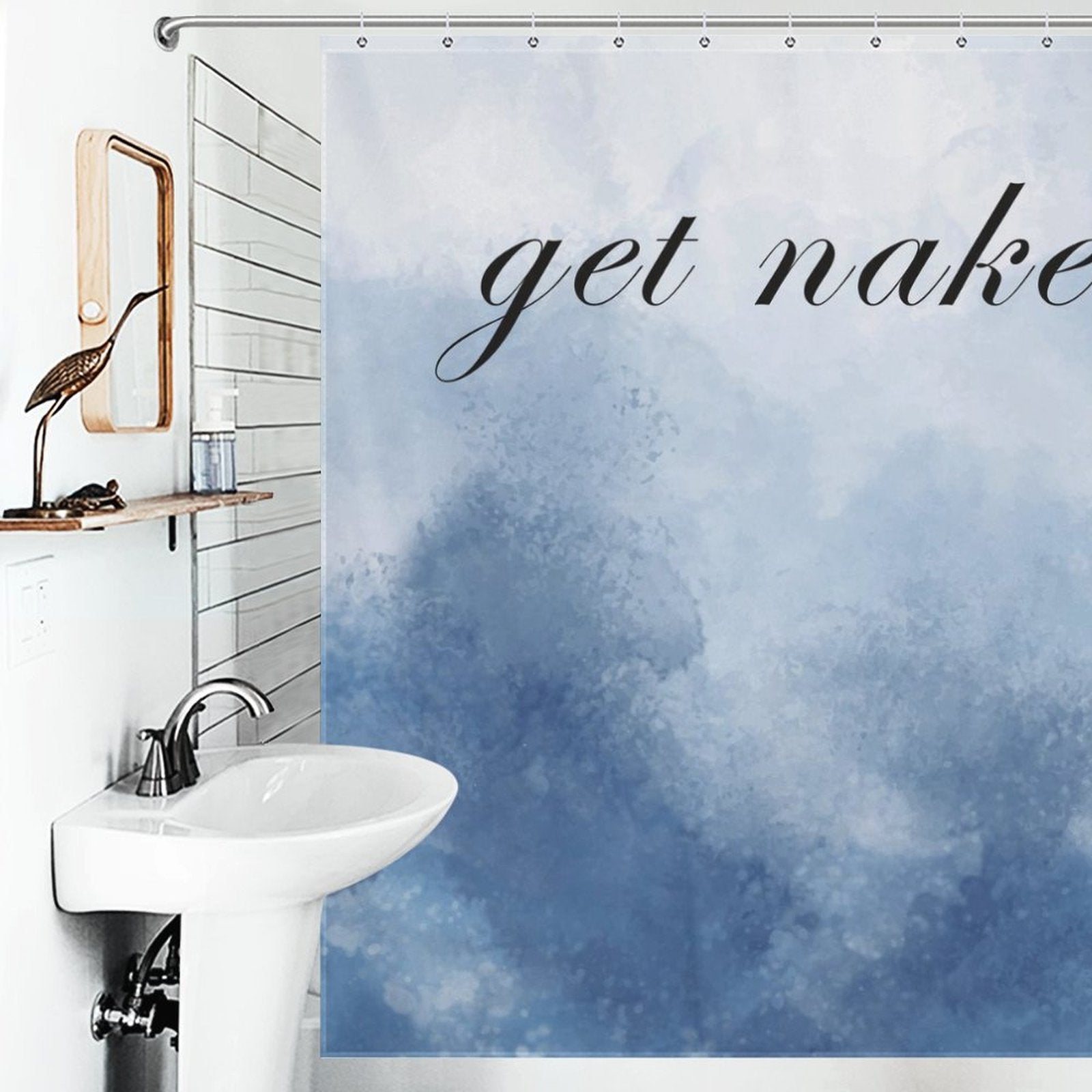 A bathroom with a white sink, a wall mirror with a wooden frame, and an abstract blue shower curtain featuring the humorous "Funny Letters Abstract Blue Get Naked Shower Curtain-Cottoncat" design by Cotton Cat.