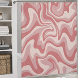 Vintage Modern Wave 70s Cute Wavy Swirl Retro Pink Abstract Shower Curtain-Cottoncat by Cotton Cat hanging in a bathroom with white shelving and neatly folded towels. A wicker basket is placed below the shelves.