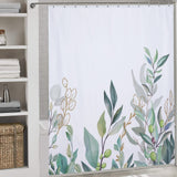 A **Watercolor Sage Green Eucalyptus Botanical Leaves Shower Curtain-Cottoncat** from **Cotton Cat** hangs in a bathroom next to shelving with neatly folded towels and a woven basket.