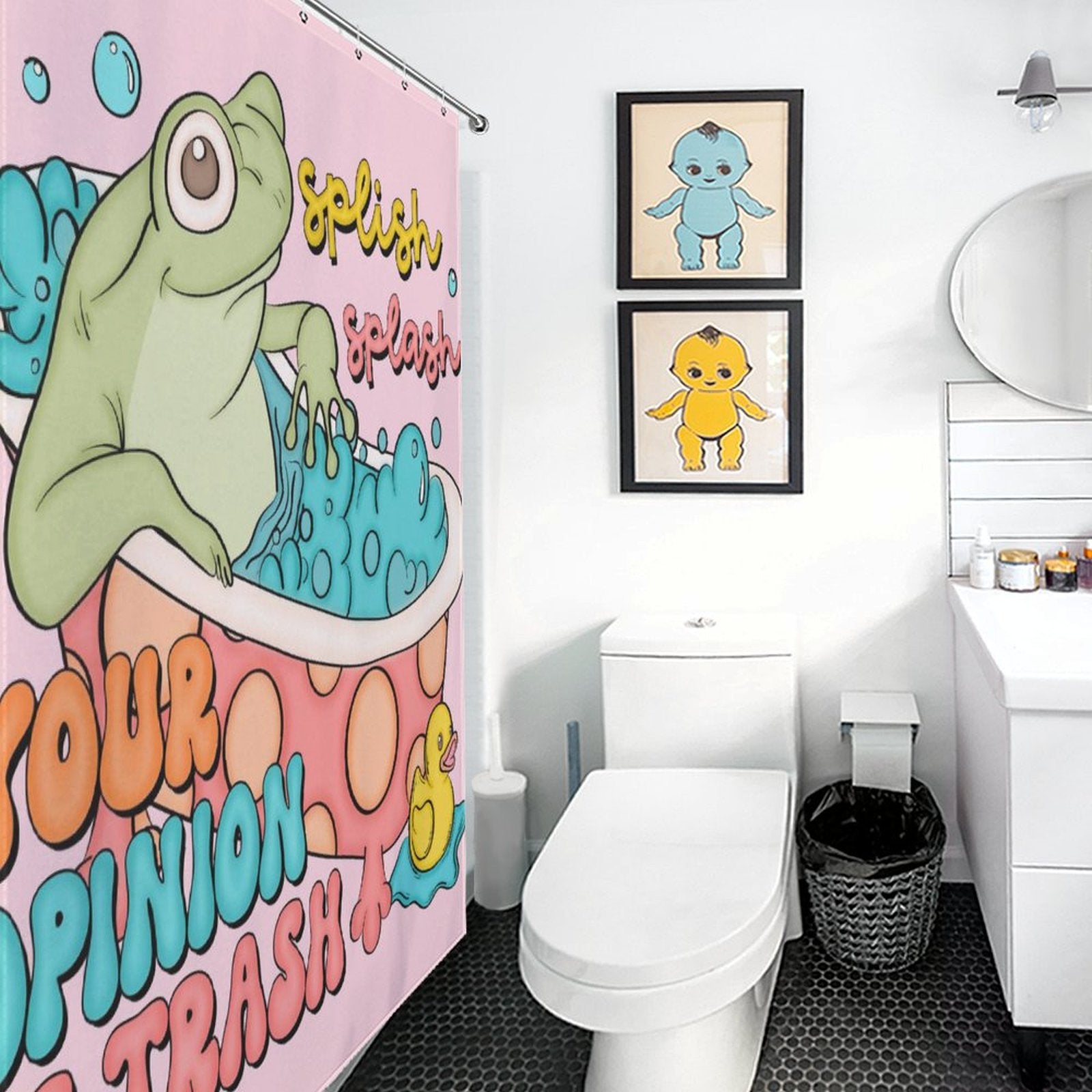 Bathroom with a white toilet, sink, trash bin, and mirror. There's a Cotton Cat Funny Humor Sarcastic Froggy Shower Curtain-Cottoncat featuring a frog in a bath with the text "Your opinion is trash," and two framed cartoon art pieces on the wall.