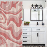 A modern bathroom with a white vanity, black hardware, and a mirror. The shower curtain features the Vintage Modern Wave 70s Cute Wavy Swirl Retro Pink Abstract Shower Curtain-Cottoncat by Cotton Cat. A row of three lights hangs above the mirror.