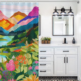 A bathroom featuring a vibrant Nature Forest Lake Watercolor Art Painting Landscape Colorful Green Mountain Abstact Shower Curtain-Cottoncat by Cotton Cat, a white vanity with black handles, a mirror, a sink, and a black light fixture with three bulbs.