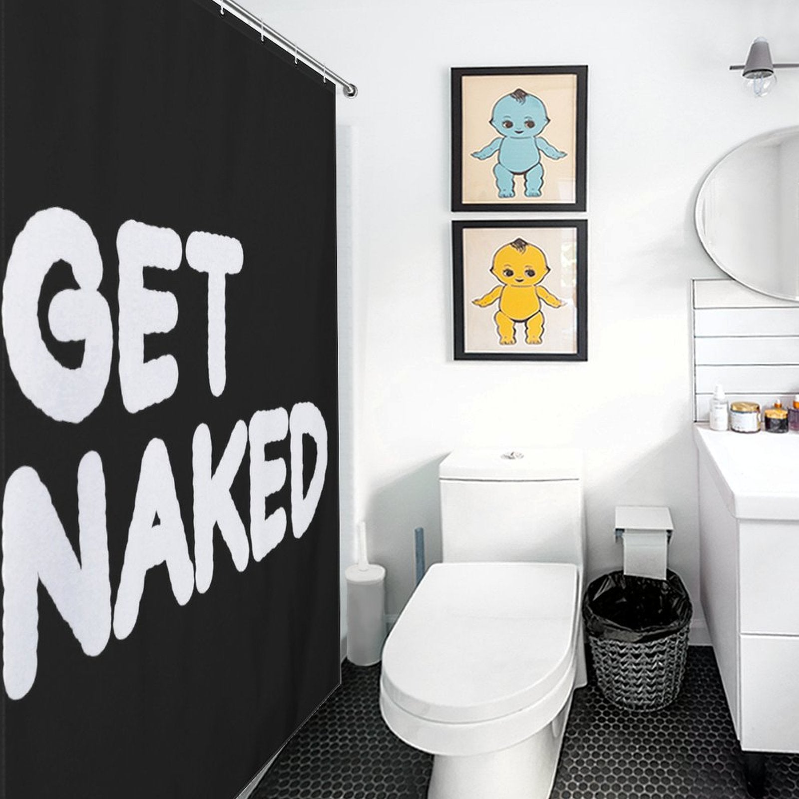 Modern bathroom with a Funny Black and White Letters Get Naked Shower Curtain-Cottoncat by Cotton Cat. The room includes a toilet, a countertop with a round mirror, and two framed prints of cartoon characters on the wall.