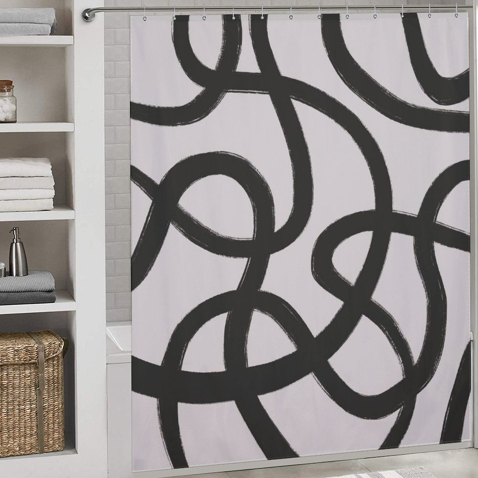 A bathroom scene with a Modern Geometric Art Minimalist Curve Black Line Black and Grey Abstract Shower Curtain-Cottoncat by Cotton Cat featuring a white background and large, minimalist black curve lines. To the left, there are shelves holding folded towels and two small jars. A wicker basket is below.