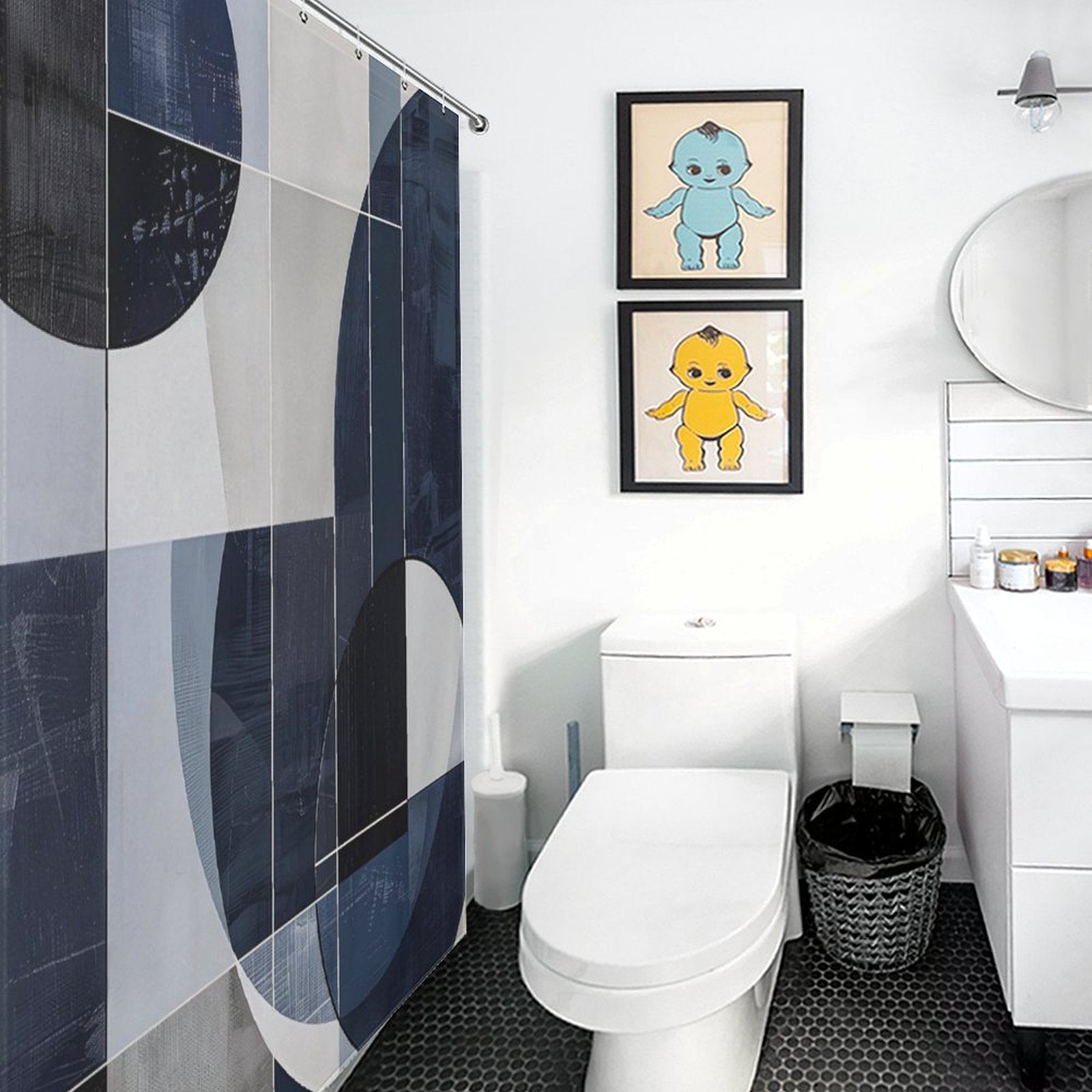 Modern bathroom with a Cotton Cat Geometric Deep Blue Abstract Art Mid-Century Modern Style Shower Curtain in blue and white, a white toilet, and sink. Two framed cartoon prints on the wall complement the round mirror above the sink. Geometric abstract art is subtly showcased in the black hexagonal floor tiles.