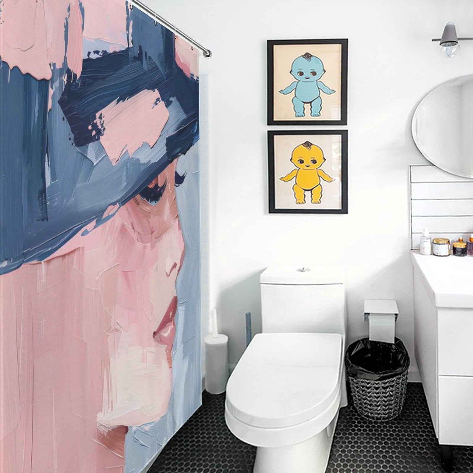 A bathroom with white walls, a toilet, a vanity with a sink, and two framed artworks of cartoon babies on the wall. A Cotton Cat Mid Century Women Face Abstract Aesthetic Oil Painting Modern Art Blush Pink Navy Blue Cream Shower Curtain is prominently displayed.
