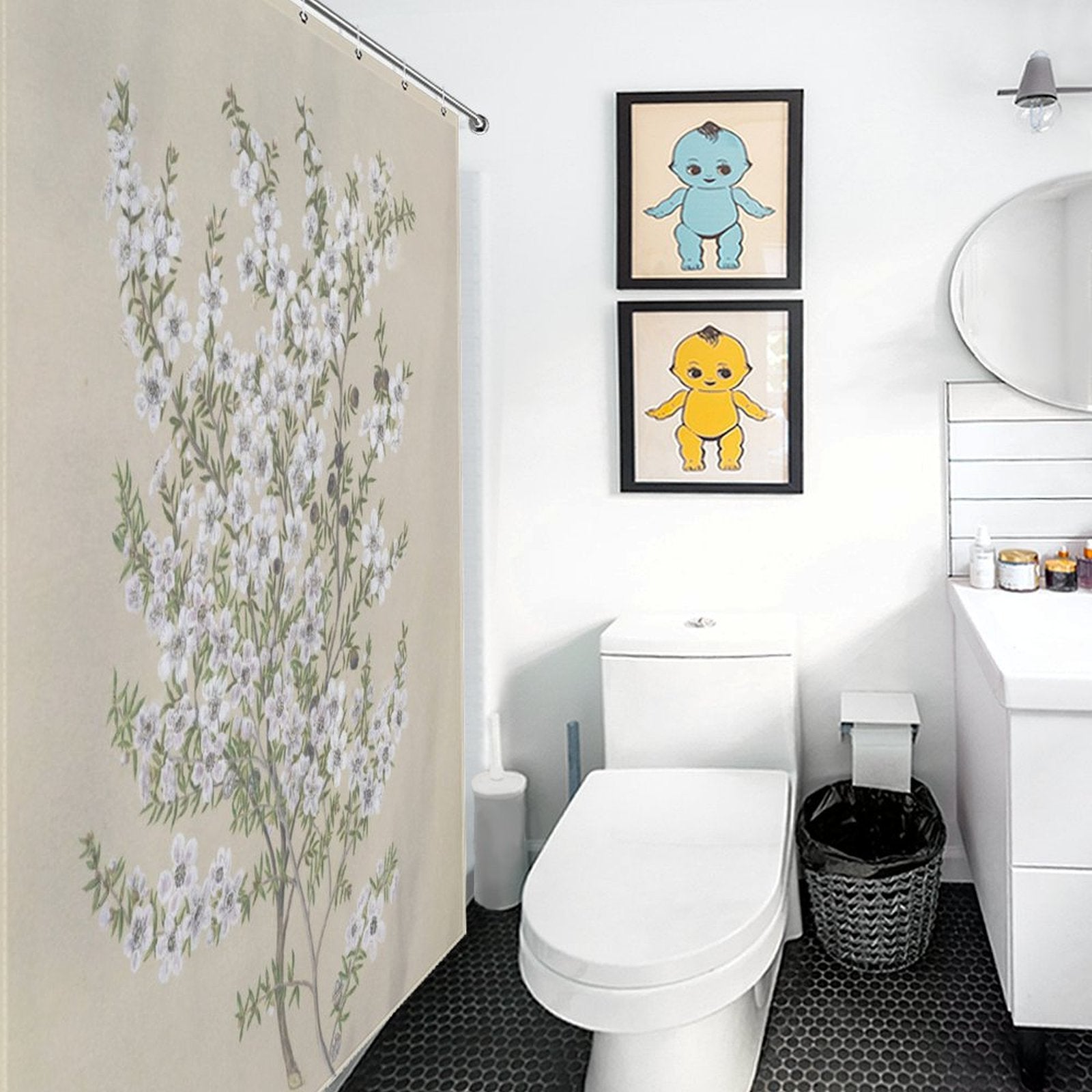 A nature-themed bathroom featuring a toilet, a vanity with a sink, a round mirror, and framed artwork of blue and yellow cartoon characters hanging on the wall. The Retro Green Flower Shower Curtain-Cottoncat by Cotton Cat adds a nostalgic touch to this cozy space.