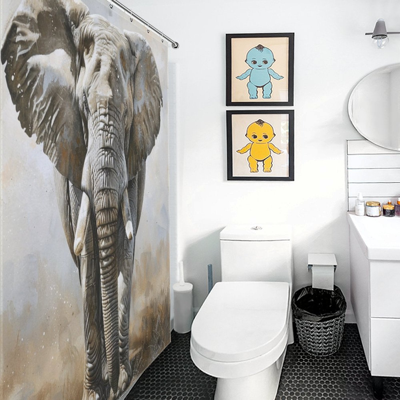 A white bathroom features an Artistic Grey Elephant Shower Curtain-Cottoncat by Cotton Cat, a toilet, and a sink with a round mirror. Two framed pictures of blue and yellow cartoon characters add charm to the wall, enhancing the overall bathroom decor.