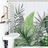 A tropical bathroom with a waterproof Monstera Leaf Jungle Shower Curtain adorned with Monstera leaves from Cotton Cat.