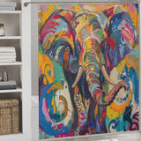 A brightly colored, multi-colored shower curtain featuring a happy elephant design is hanging in a bathroom with white tile walls, shelves with folded towels, and a wicker basket. This cheerful piece of bathroom decor adds a playful touch to the space. The Multi Colored Happy Elephant Shower Curtain-Cottoncat by Cotton Cat brings vibrant charm to any bathroom setting.