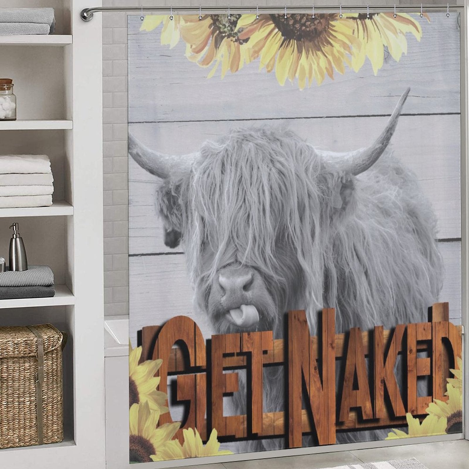 The Highland Cow Sunflowers Get Naked Shower Curtain-Cottoncat by Cotton Cat features a picture of a Scottish Highland cow and the words "GET NAKED" in large wooden letters, surrounded by vibrant sunflowers. Towels and shelves are visible on the left, adding a touch of rustic charm to your bathroom décor.