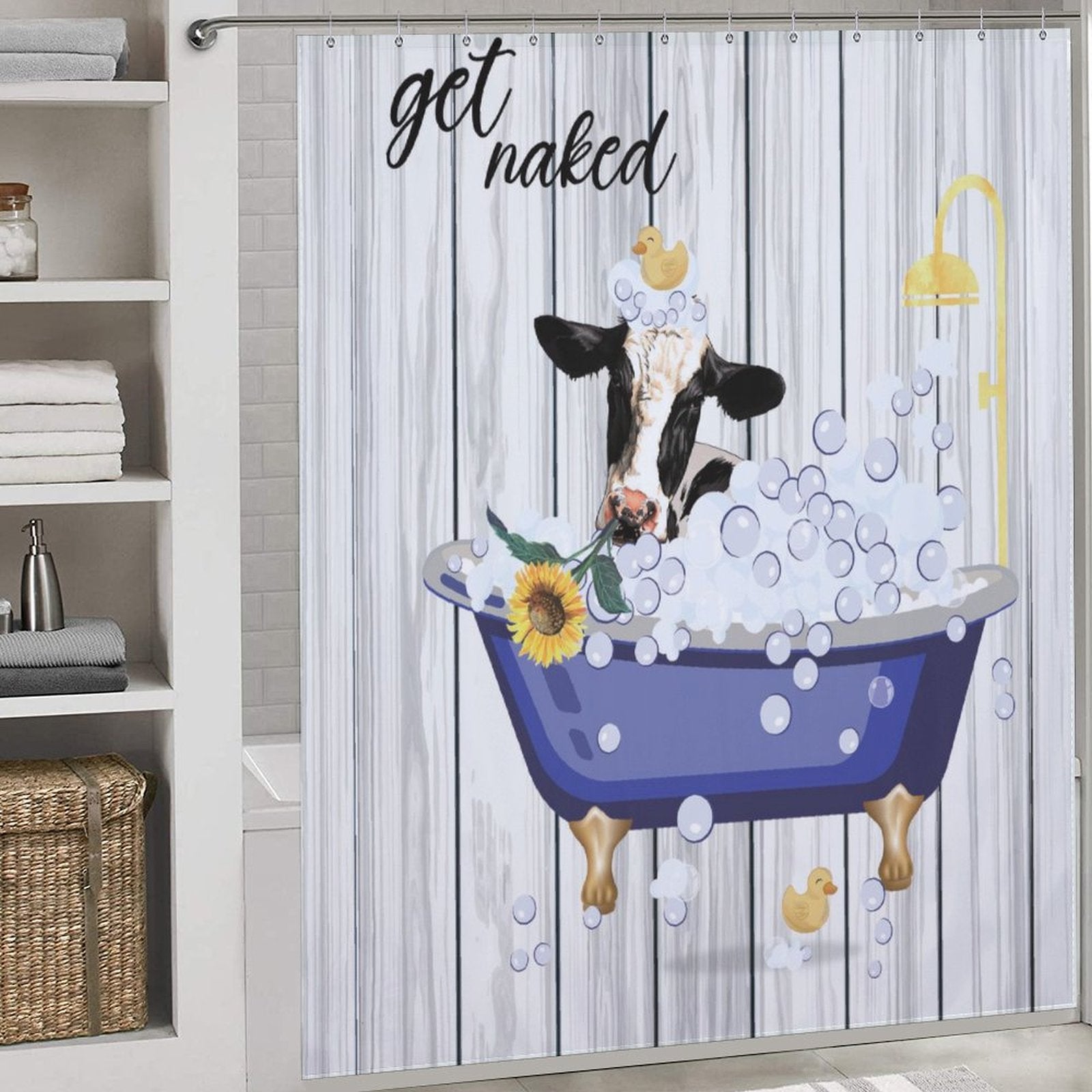 The Funny Cow Sunflowers Get Naked Shower Curtain-Cottoncat by Cotton Cat showcases a cow taking a bubble bath in a blue tub with rubber ducks, sunflowers, and the playful text "get naked" above. Towels and toiletry items are neatly arranged on shelves nearby.