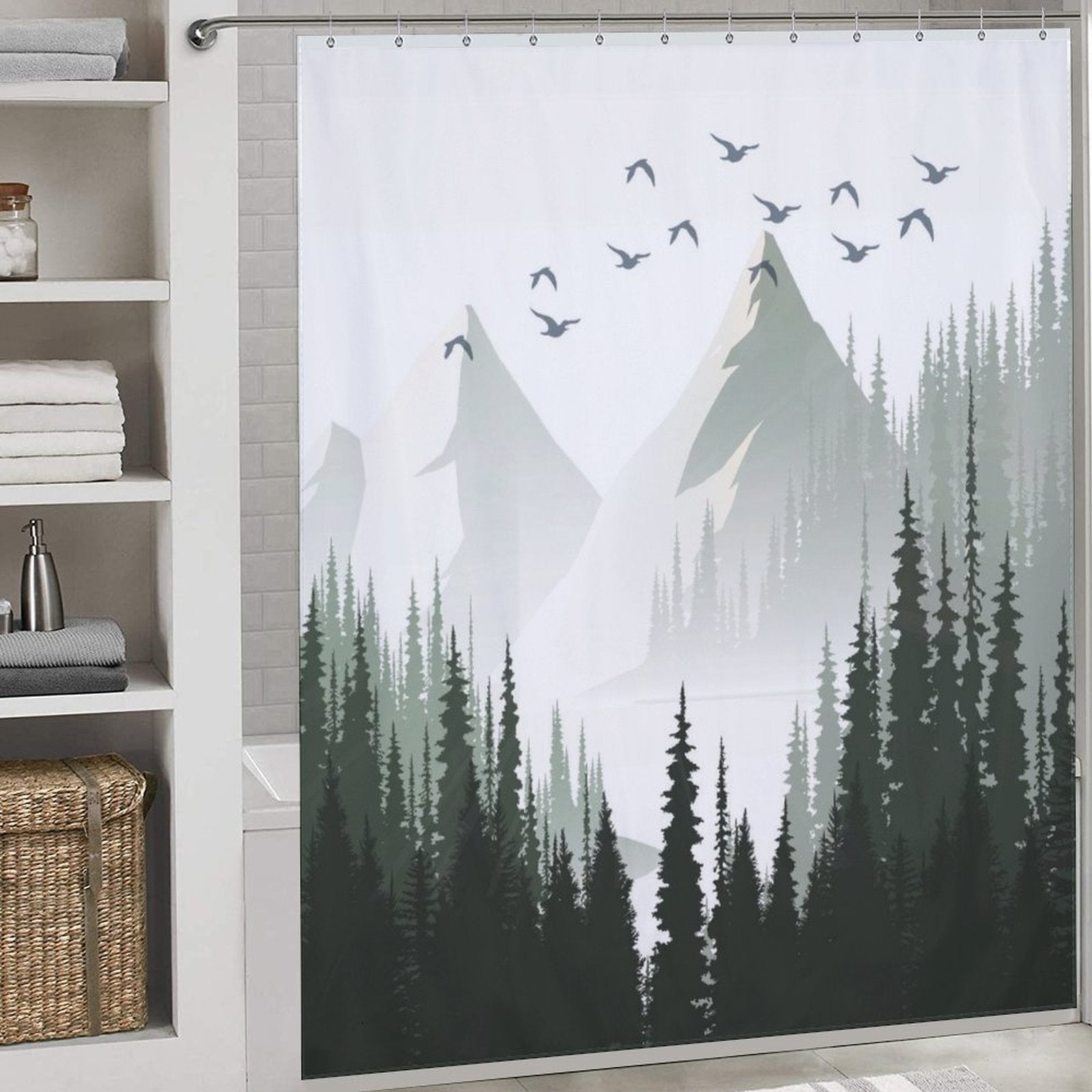 Transform your bathroom into a serene escape with the Green Misty Forest Shower Curtain Ombre Sage Green White Nature Tree Mountain Woodland-Cottoncat by Cotton Cat, showcasing an intricate mountain and forest design. Evergreen trees and flying birds enhance the nature scene, beautifully complementing shelves laden with towels and a woven basket.