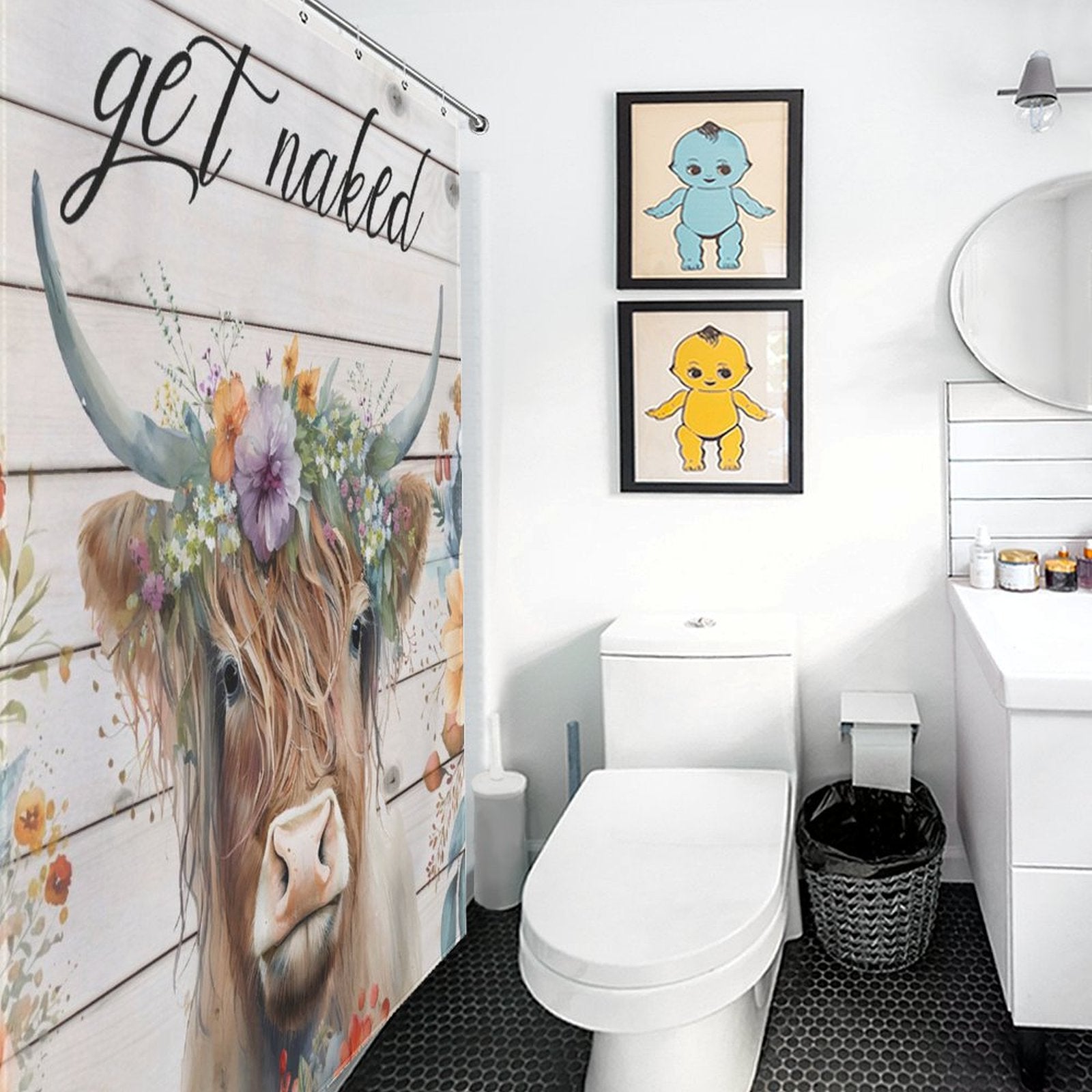 A bathroom with a toilet, sink, and decorative elements. A Cotton Cat Funny Letters Get Naked Flower Highland Cow Shower Curtain-Cottoncat displays the phrase "get naked." Above the toilet are framed illustrations of cartoon characters.