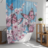 A Vintage Pink Butterfly Flying over Water Shower Curtain-Cottoncat by Cotton Cat adorns a bright bathroom, featuring cherry blossoms against a serene blue and white backdrop. The water-resistant fabric shower curtain adds timeless charm to the vintage decor, complemented by a basket, plant, and shelves.