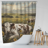 The Farmhouse Cow Graze Sunflower Shower Curtain-Cottoncat by Cotton Cat features a picturesque scene of cows grazing among sunflowers in a rural landscape, set against rolling hills and a cloudy sky. This charming shower curtain hangs over a white bathtub in a modern bathroom, adding a touch of farmhouse elegance.