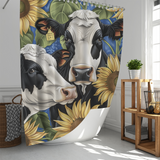 The Cotton Cat Rustic Cow Sunflower with Green Leaf Shower Curtain features two cows and sunflowers, one cow adorned with a cowbell and a visible price tag. The charming curtain is displayed in a bright, well-lit bathroom decorated in farmhouse style, complemented by a wicker laundry basket and a small plant.