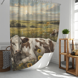 A Farmhouse Cow Graze Sunflower Shower Curtain-Cottoncat by Cotton Cat hangs in a white bathroom, next to a wicker laundry basket and wooden shelving unit.